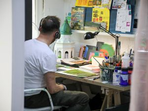An artist wearing headphones working in his studio.